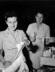 WWII nurses tending to a patient's bandaged leg, 25th infantry division
