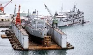 Gray ship inside a dry dock with cranes, part of an ABSD.
