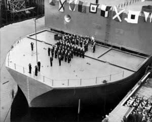 ABSD crew poses on a ship's bow with signal flags.