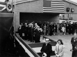 ABSD: Dignitaries in uniform and civilians salute under US flag.
