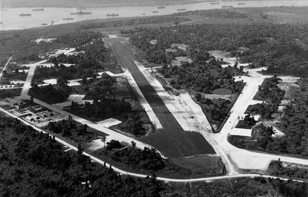 Aerial view of a jungle airfield with a long runway.