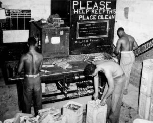 Historical Aore: Men working at a cleaning station with a "Please Help Keep This Place Clean" sign.