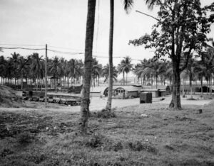 Aore historical site with Quonset huts, trucks, and palm trees