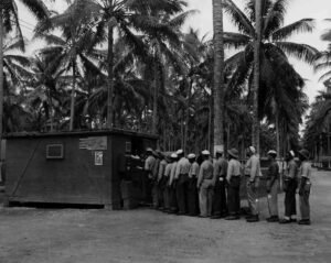Men in uniform line up outside a building on Aore, surrounded by palm trees.