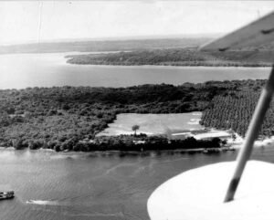 Aerial view of Aore island, showing lush vegetation, a clearing, and water.