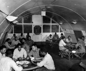 Men playing cards in a Quonset hut on Aore Island during WWII.