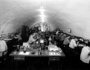 Men working on equipment in a long, arched workshop during historical maintenance.