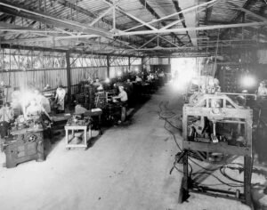 Historical maintenance workshop with men working on machinery