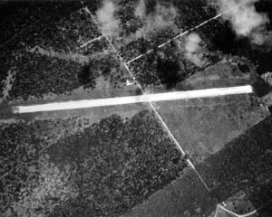 Aerial view of a rural airstrip with surrounding trees and fields.