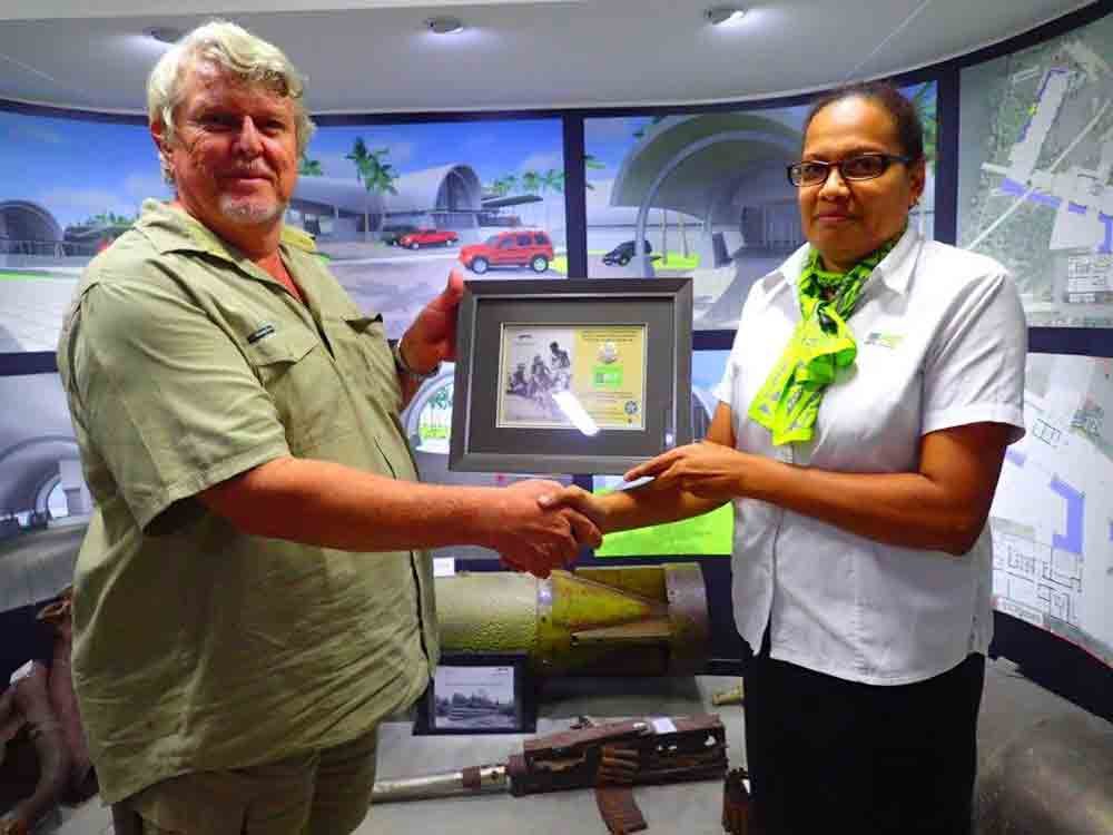 Man and woman shake hands, presenting a framed award at BSP Navara sponsorship event.