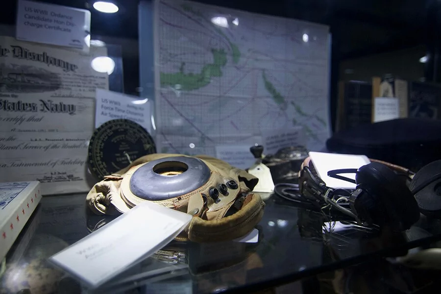 WWII aviation artifacts: headset, map, discharge certificate in a gallery display.
