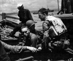 Marines in a boat, some injured, during WWII landing operations.