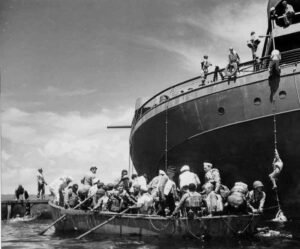 USS Coolidge passengers disembarking onto a smaller boat during WWII.
