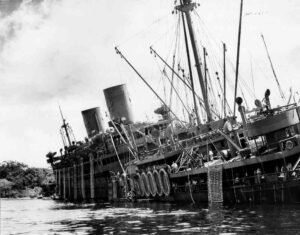The USS Coolidge, a troop transport ship, is listing heavily in the water.