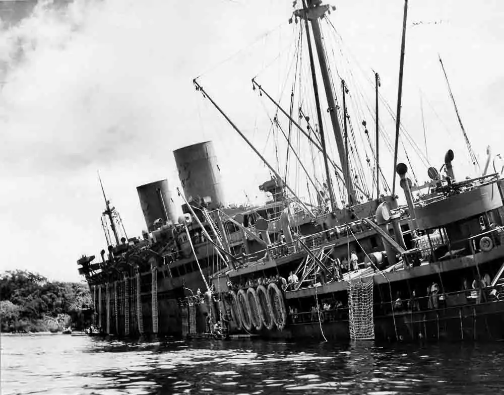 The USS Coolidge, a troop transport ship, is listing heavily in the water.