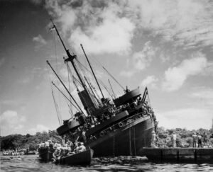 SS Coolidge shipwreck with people in lifeboats and on deck.