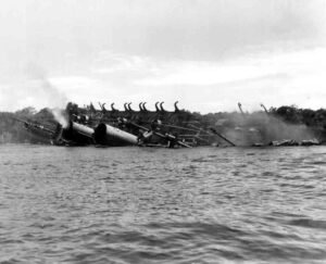 USS Coolidge sinking, smoke billowing from its hull, listing heavily in the water.