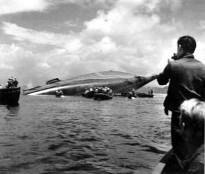 The SS Coolidge capsized, with rescue boats and onlookers in the water.
