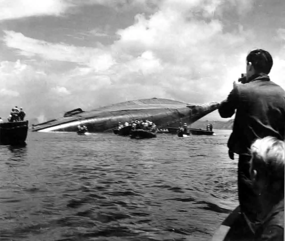 The SS Coolidge capsized, with rescue boats and onlookers in the water.