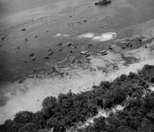 WWII aerial view of numerous ships and landing craft near a tropical island, possibly related to the Coolidge.