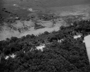 Aerial view of Coolidge beach with numerous boats and people on the shore.