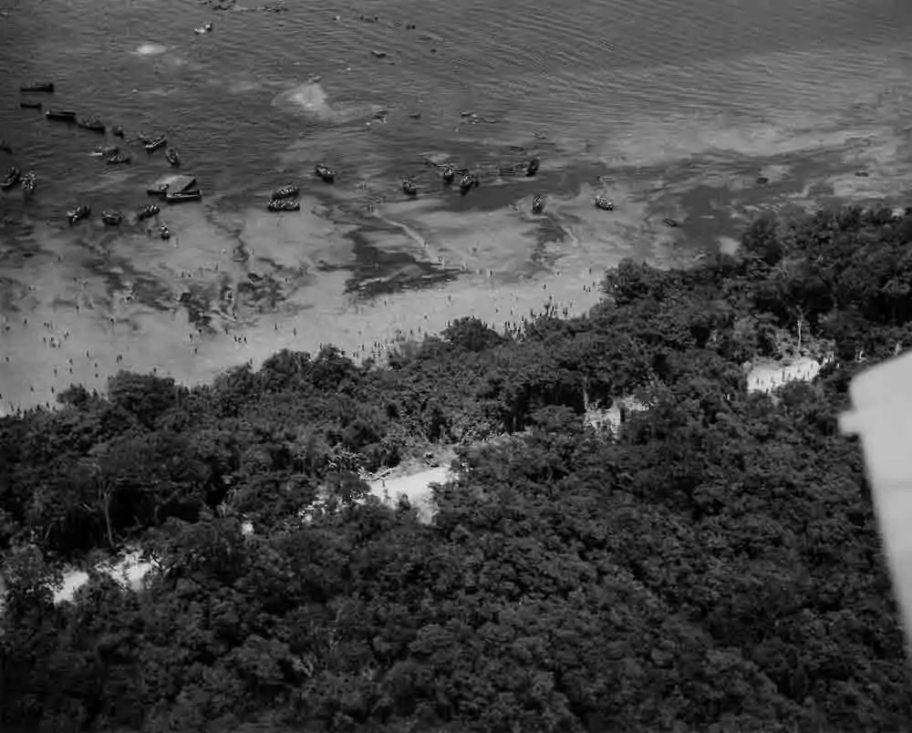 Aerial view of Coolidge beach with numerous boats and people on the shore.