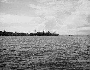 SS Coolidge shipwreck, a historical vessel partially submerged in calm water with trees on the horizon.