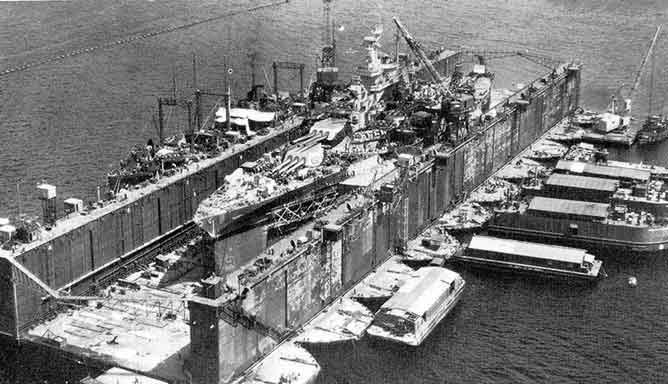 Floating dry dock holding a large warship for repairs.