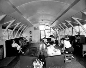 Nurses gathered in a sunlit lounge area of a historical hospital ward.