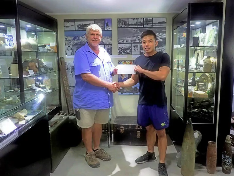 Man in blue shirt hands check to man in black shirt in museum display