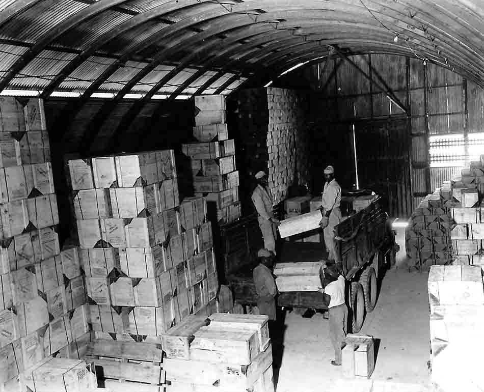 Million Dollar Point: Workers load crates onto a truck in a vast warehouse.