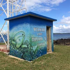 Mural on a blue building at Million Dollar Point, Vanuatu, depicting underwater scenes and text.