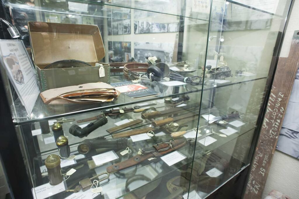 Museum display case with historical artifacts, including knives and goggles.