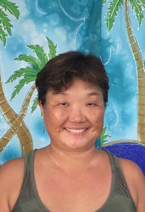 Museum team member smiling against a tropical backdrop.