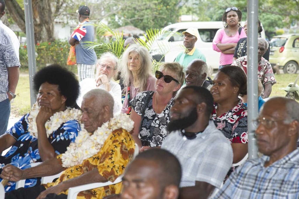 People gathered at a museum opening in a tropical setting.
