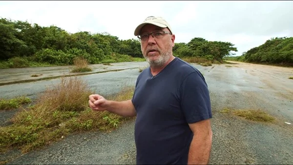 Man in cap and glasses on overgrown road, video context
