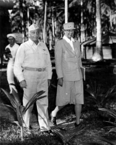 Franklin D. Roosevelt in uniform with a female officer in a tropical setting.