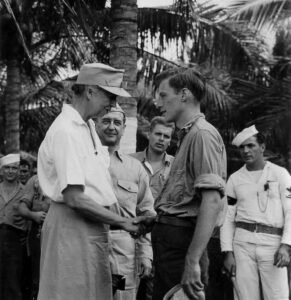 President Roosevelt shakes hands with a sailor in uniform.