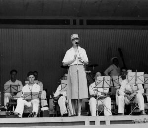 Historical band performance with a woman singing into a microphone.