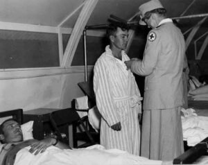 Red Cross nurse awards medal to soldier in hospital tent