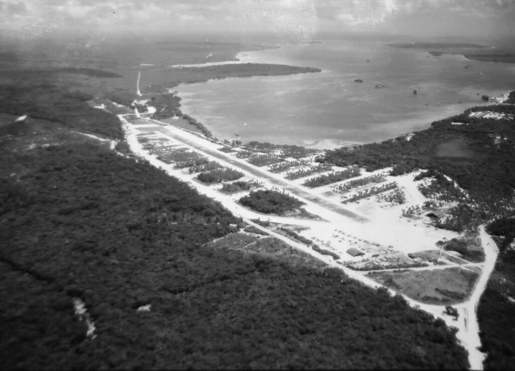 Aerial view of Santo Base, a WWII airbase with runways and buildings near a bay.