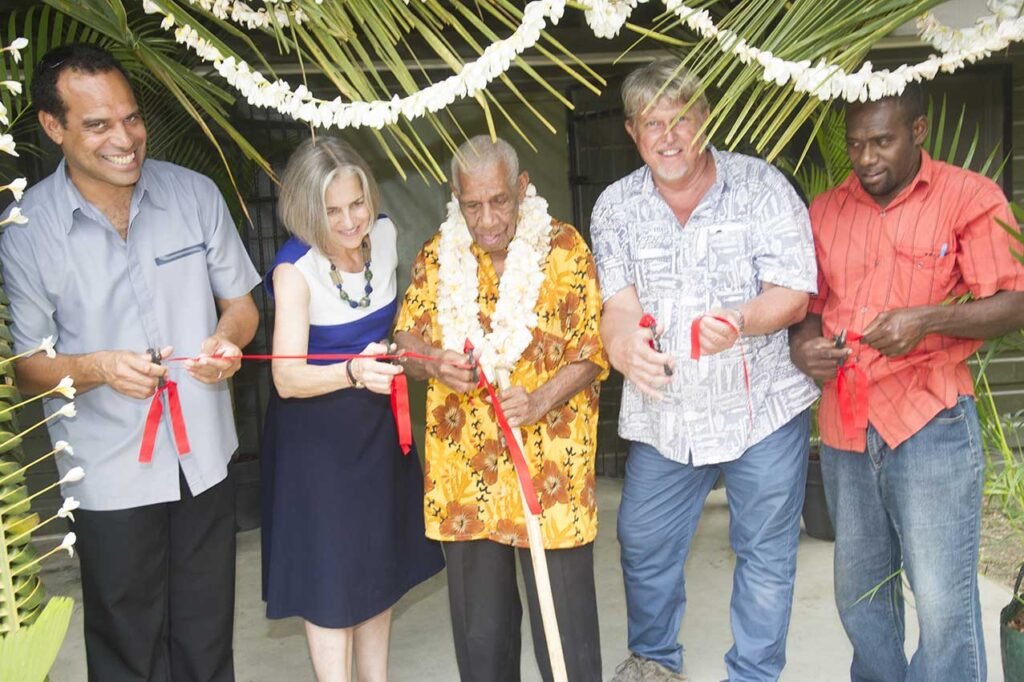 Five people cutting a ribbon at a museum opening ceremony