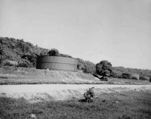 Large cylindrical fuel tanks in a tropical landscape with lush greenery.