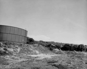 Large industrial fuel tanks on a grassy hillside