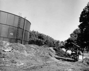 Large fuel tank labeled "42" with a ladder, near a pump and pipe.