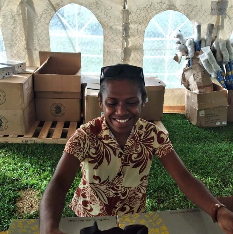 Young woman smiles at Bigfala 2021 sale, browsing bargain goods.