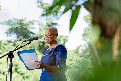 Woman speaking at podium during Coolidge Commemoration event outdoors.