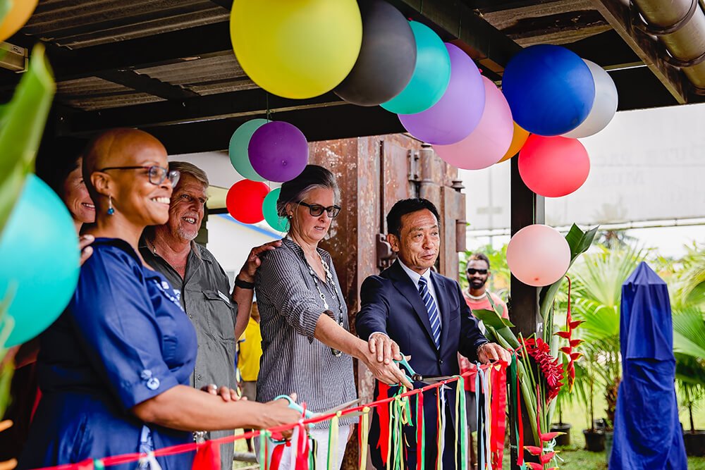 Ribbon-cutting ceremony with colorful balloons at an outdoor event.