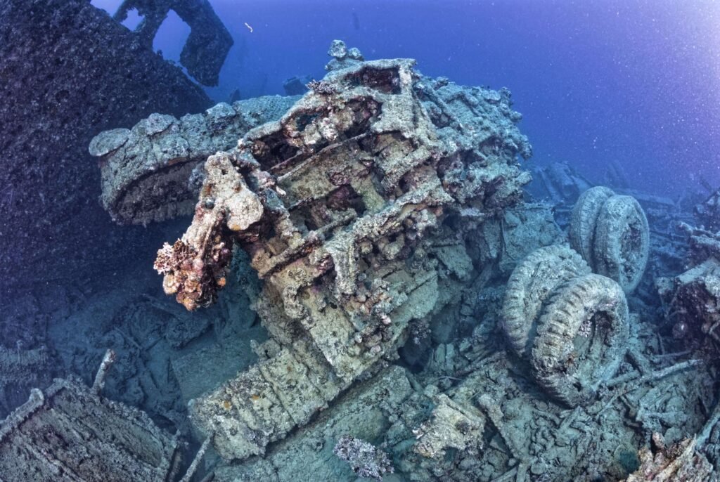 Underwater shipwreck debris with tires and coral growth.