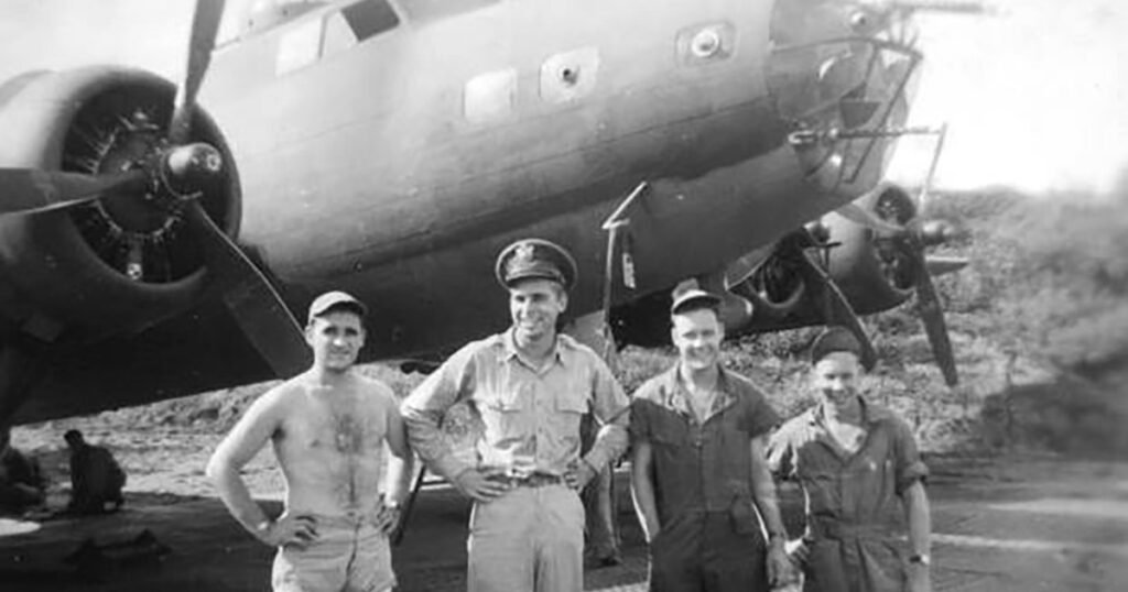 Four men in military uniforms stand before a B-17 bomber aircraft.